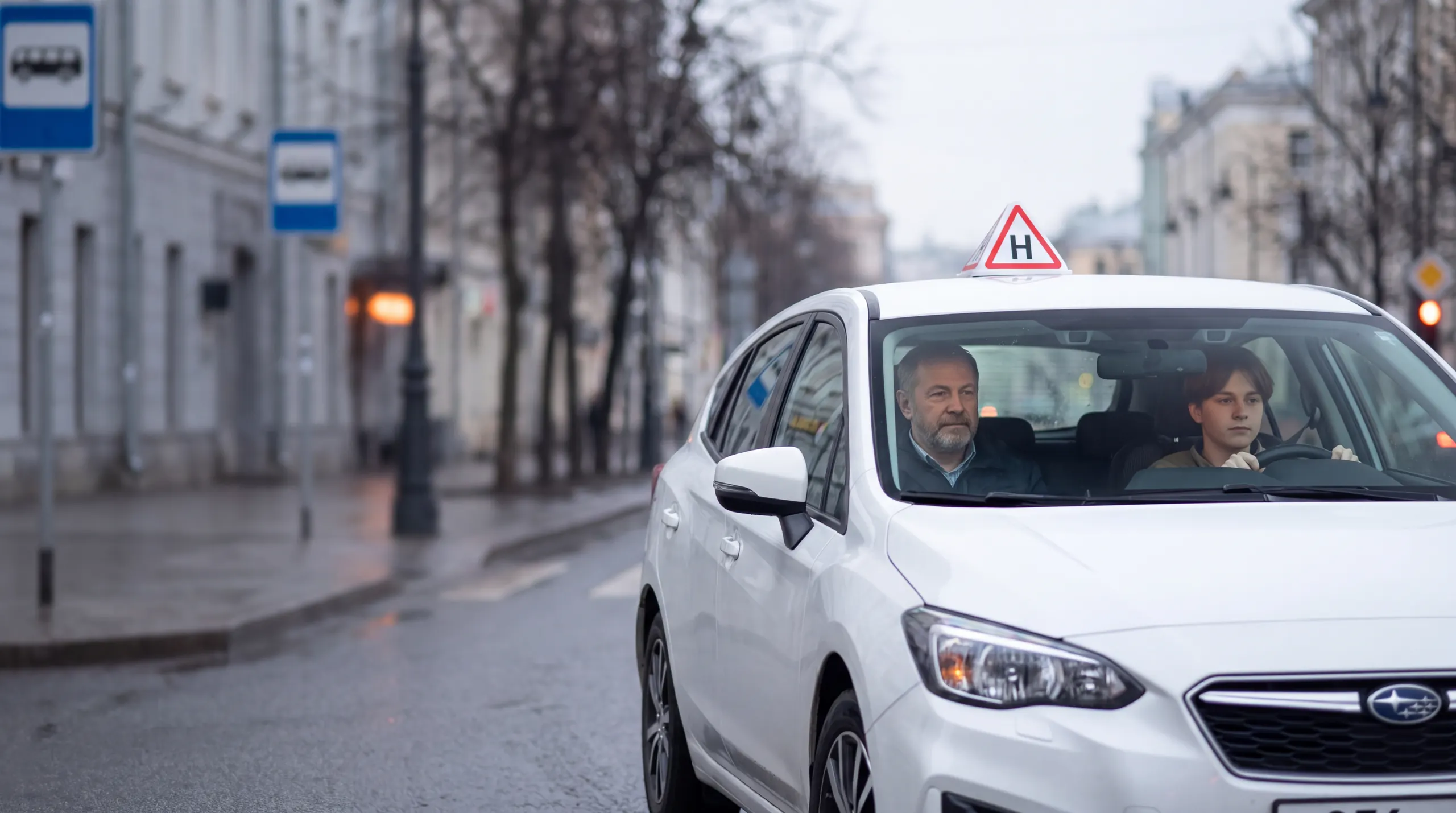 Учень за кермом навчального авто зі знаком Н, поруч інструктор