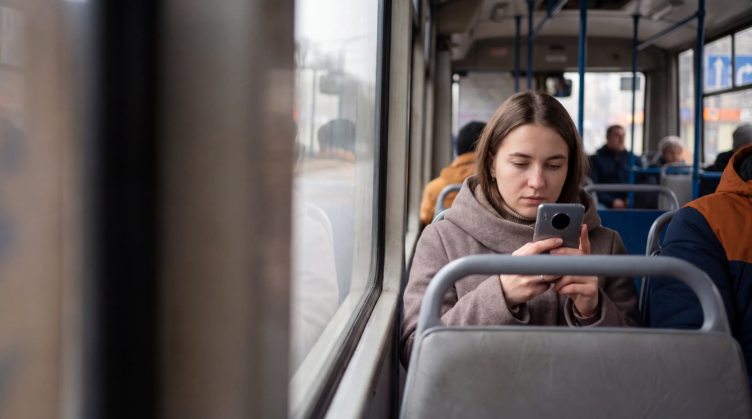 Дівчина в автобусі проходить тести ПДР на телефоні
